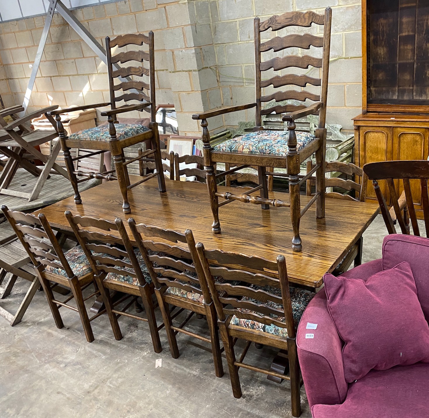 An 18th century style rectangular oak refectory dining table, length 210cm, depth 92cm, height 76cm together with a set of ten oak and beech ladder back dining chairs (two with arms) *Please note the sale commences at 9a